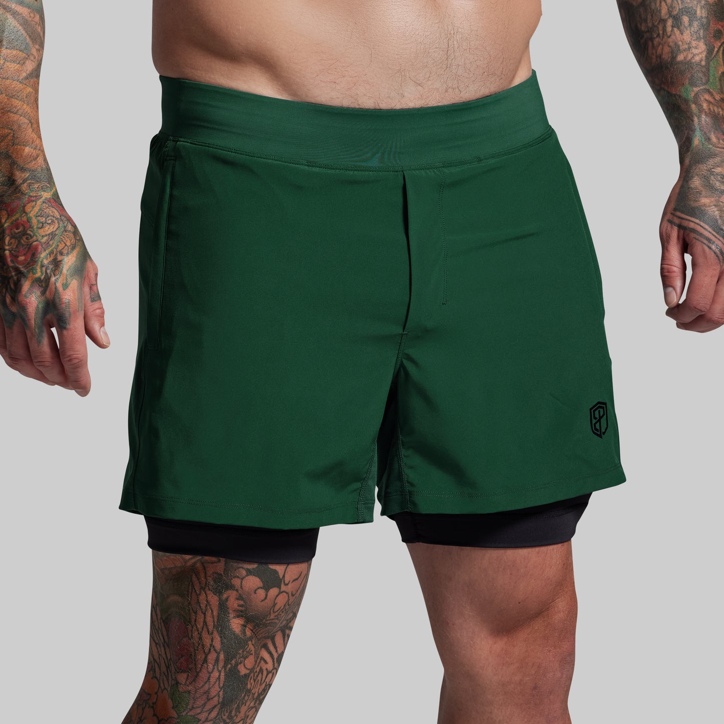 Person wearing green athletic shorts on a plain background