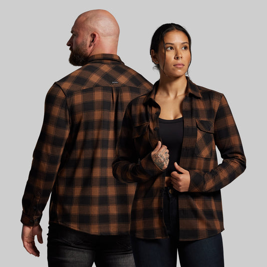 Two people wearing brown plaid shirts against a gray background