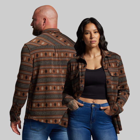 Man and woman wearing patterned shirts and jeans on a plain background