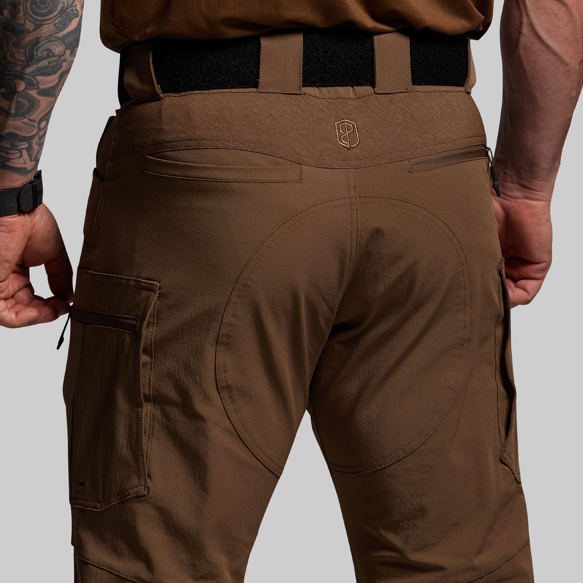Brown tactical pants with a visible brand logo on a gray background