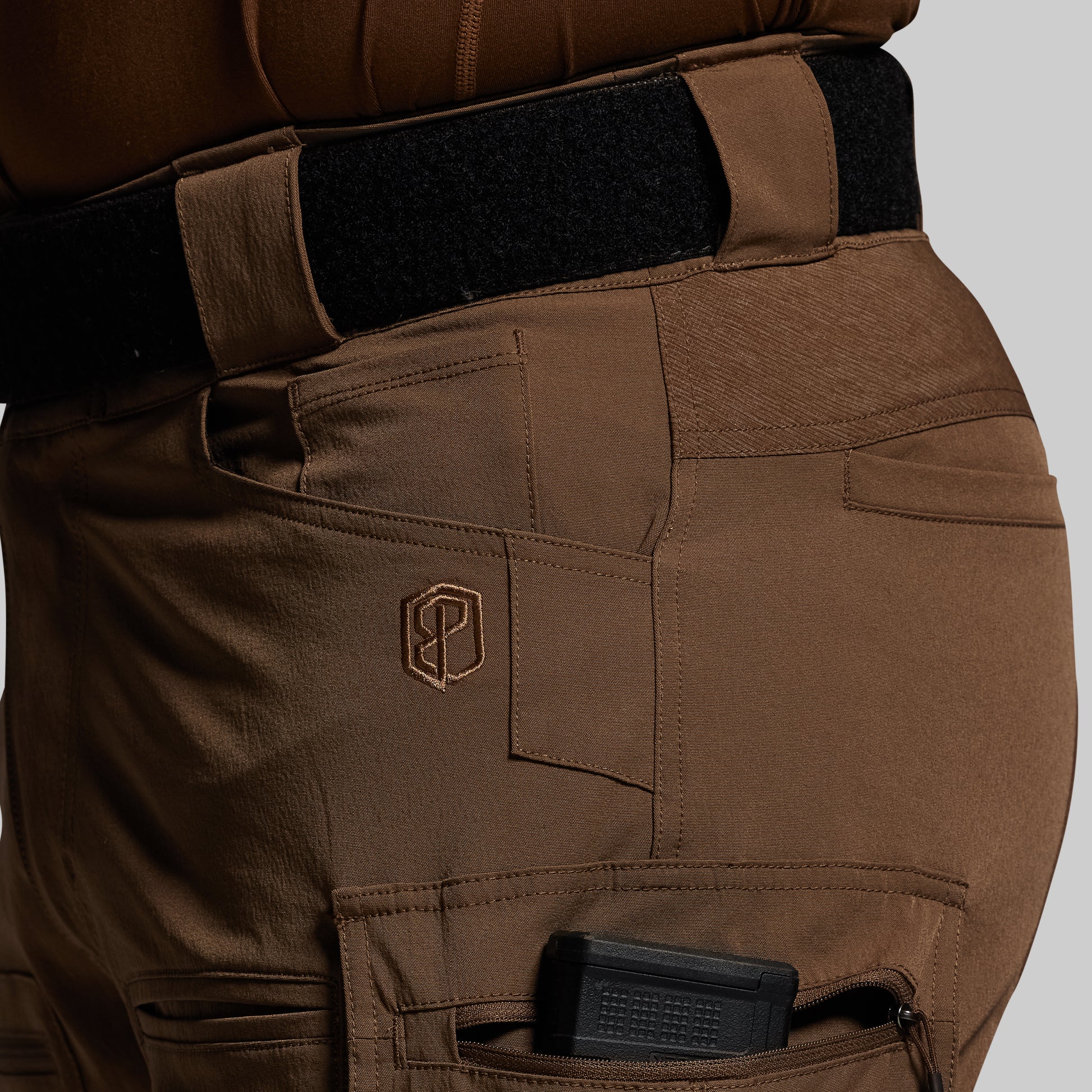 Brown tactical pants with a visible brand logo on a gray background