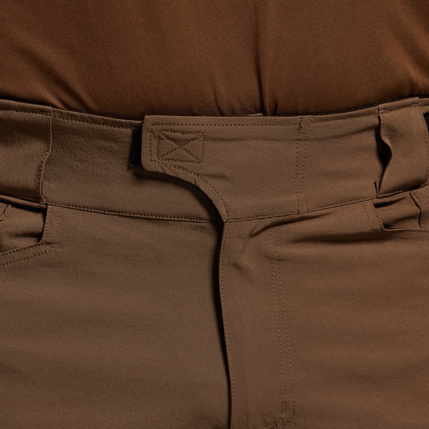 Close-up of brown pants with a focus on the waistband and pocket area.
