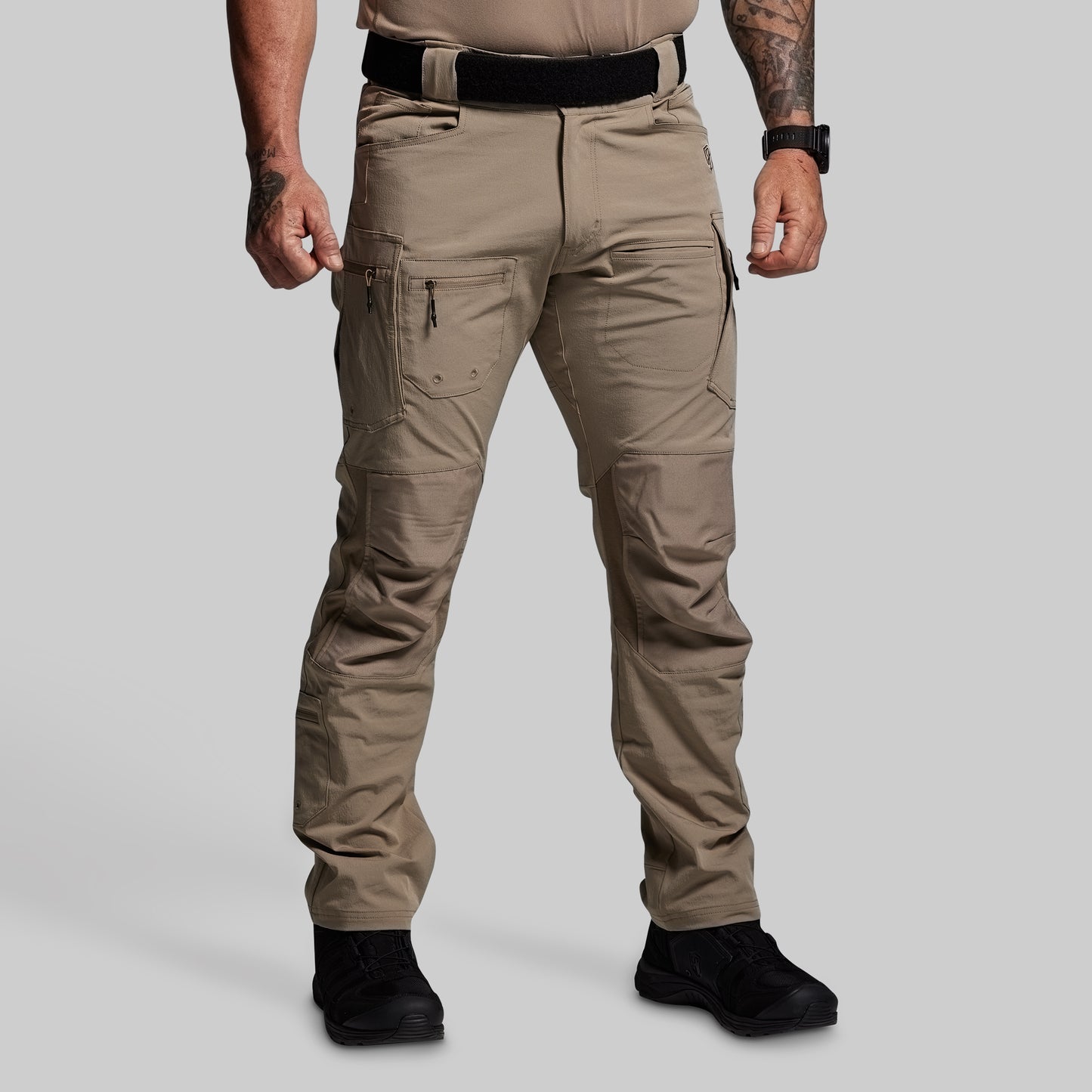 Person wearing beige tactical pants on a gray background
