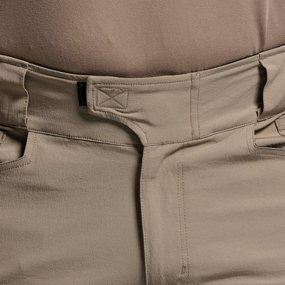 Close-up of beige pants with a brand logo on the waistband.