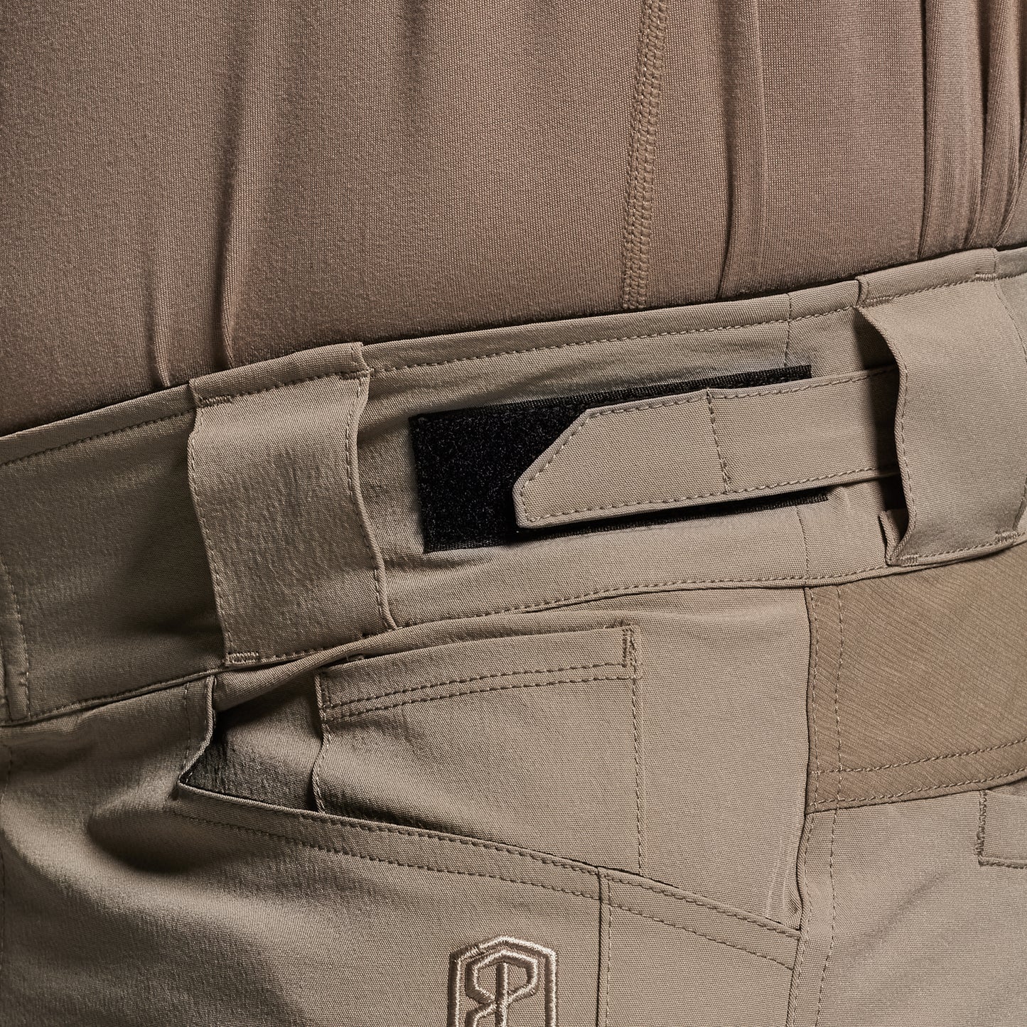 Close-up of a brown tactical pants with multiple pockets and a visible brand logo.