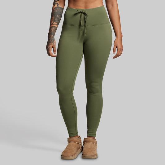 Person wearing olive green leggings on a plain background