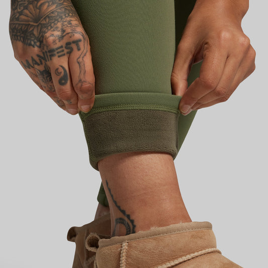 Person wearing green leggings with a plain background