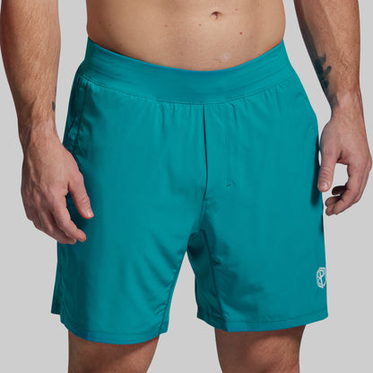 Teal shorts worn by a person on a plain background