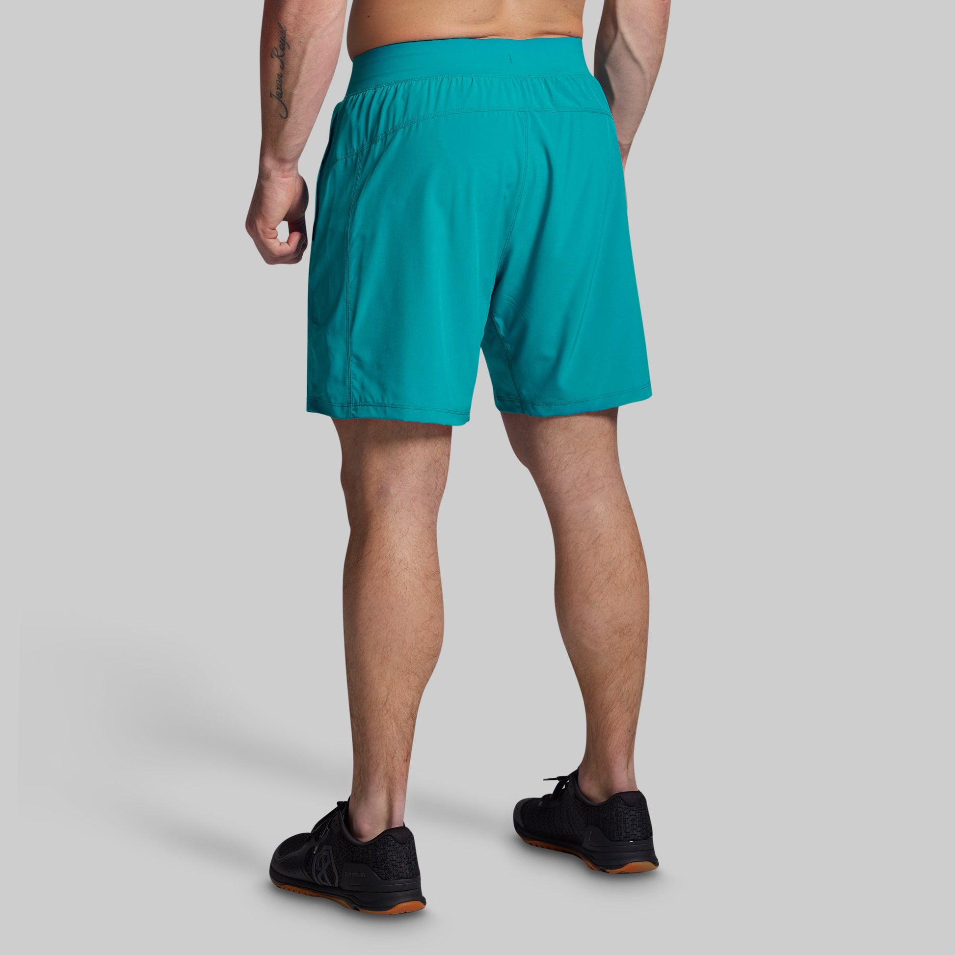 Person wearing teal shorts on a gray background