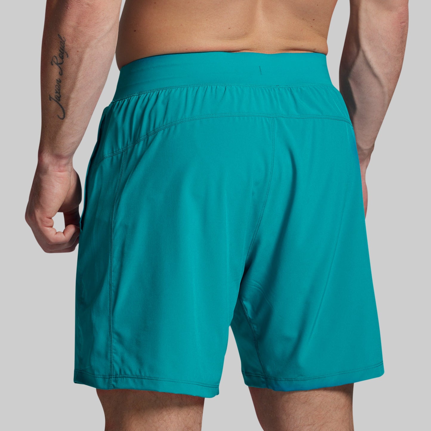 Teal shorts worn by a person on a plain background