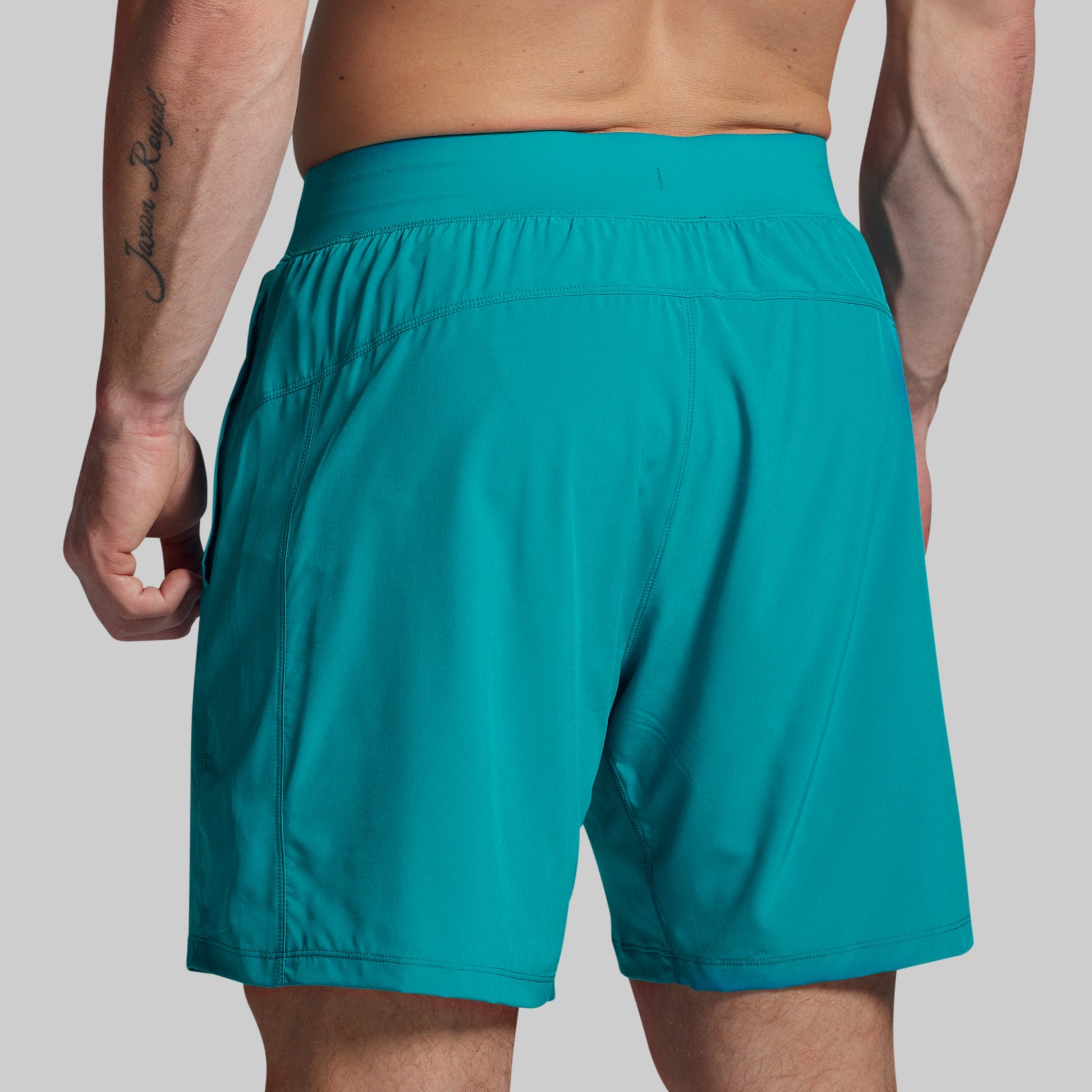 Teal shorts worn by a person on a plain background