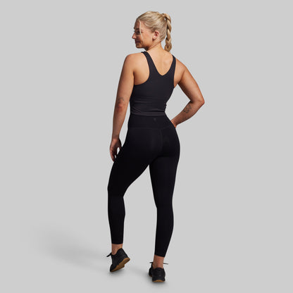 Woman wearing a black athletic outfit on a gray background