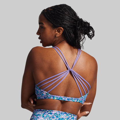 Woman wearing a colorful sports bra with a gray background
