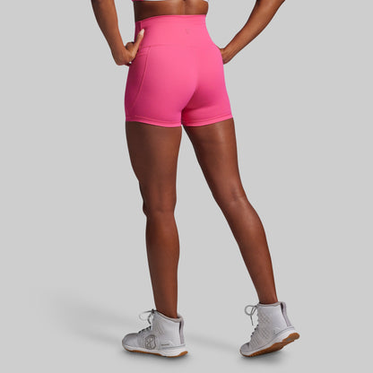 Person wearing bright pink athletic shorts on a gray background