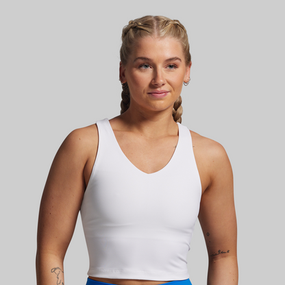 Woman wearing a white tank top against a plain background