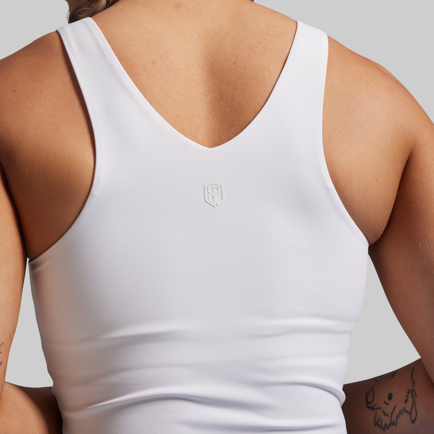 White tank top with a brand logo on a neutral background