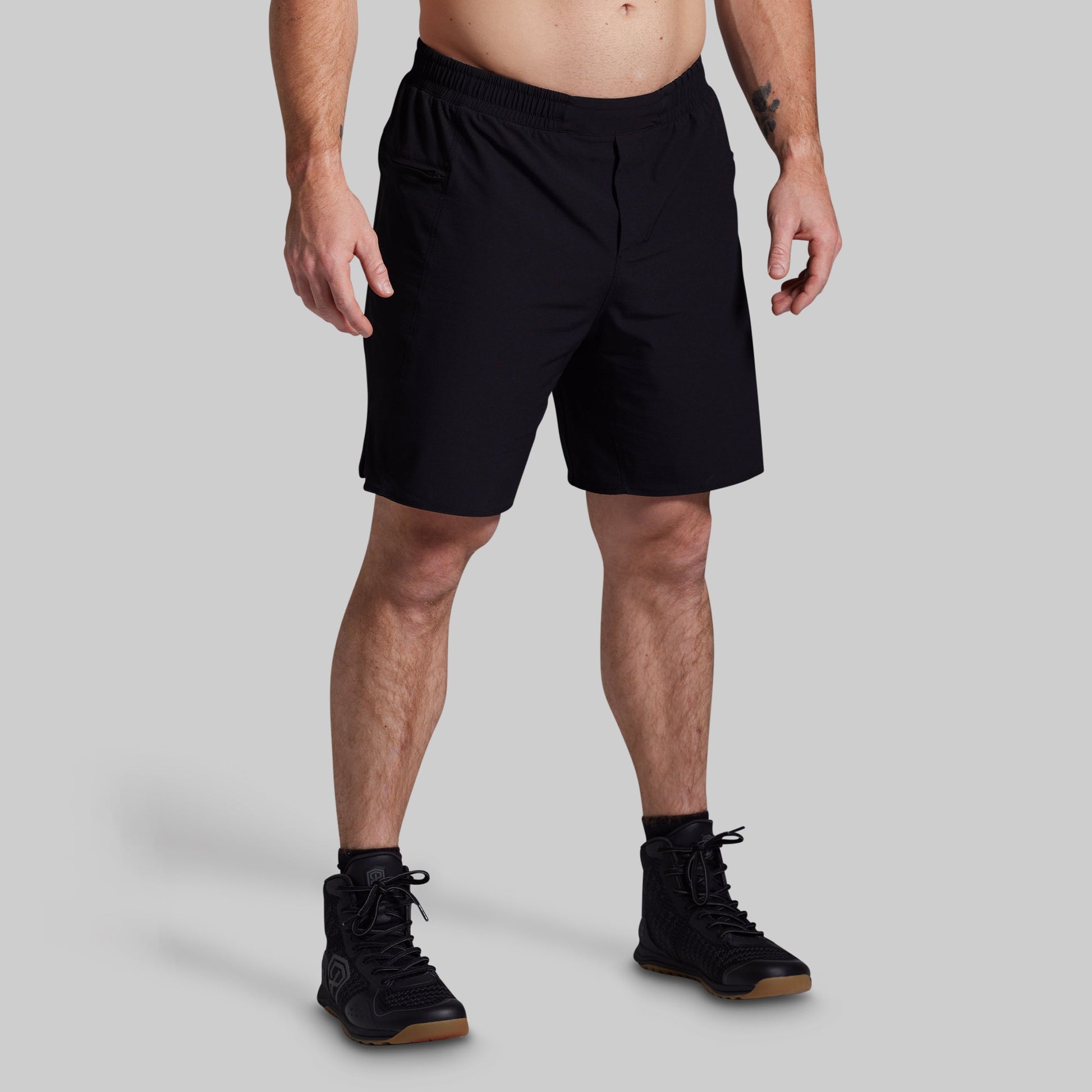 Person wearing black shorts on a gray background