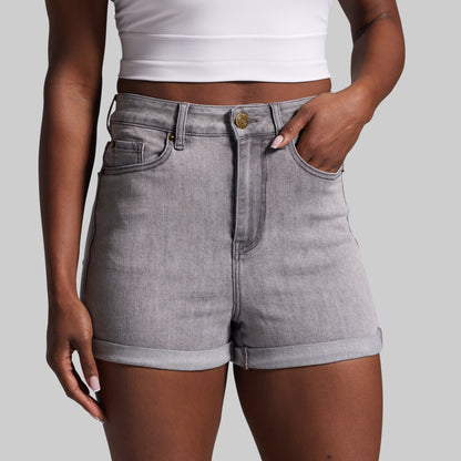 Person wearing gray denim shorts on a plain background