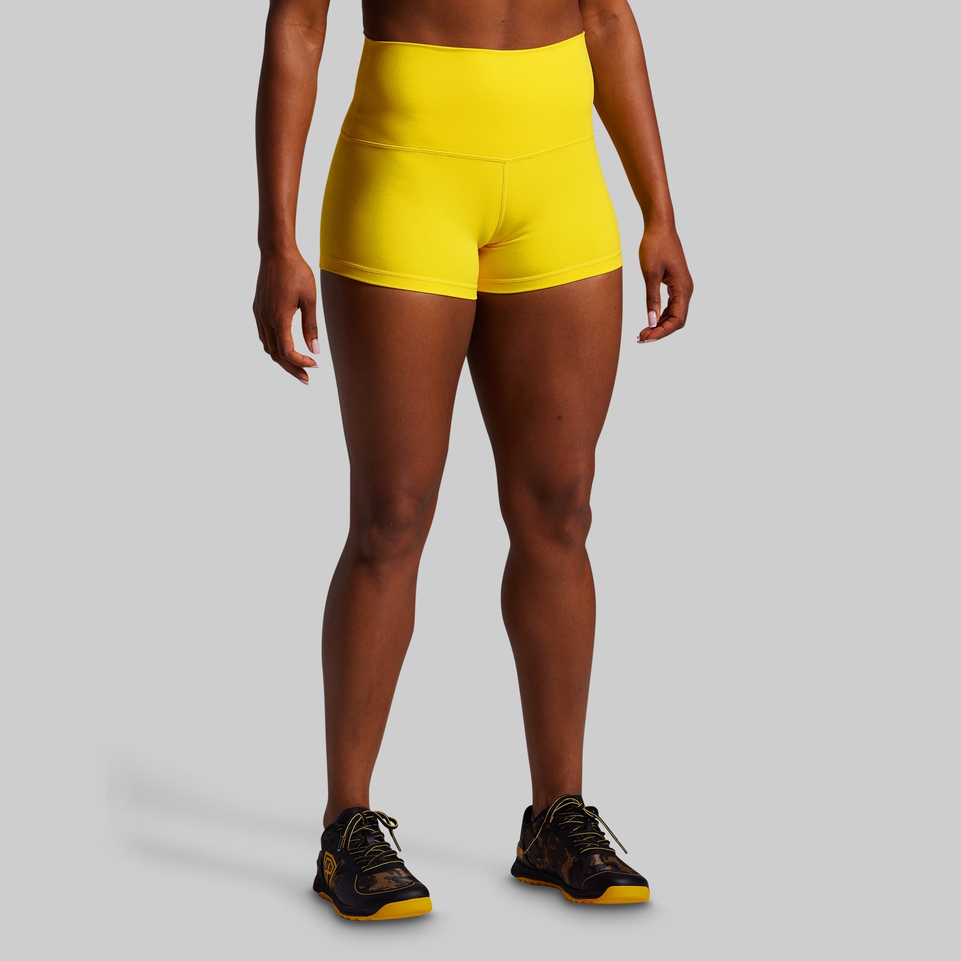 Person wearing bright yellow athletic shorts on a gray background