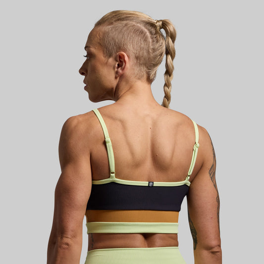 A sports bra with black, yellow, and green color blocks, featuring adjustable straps.