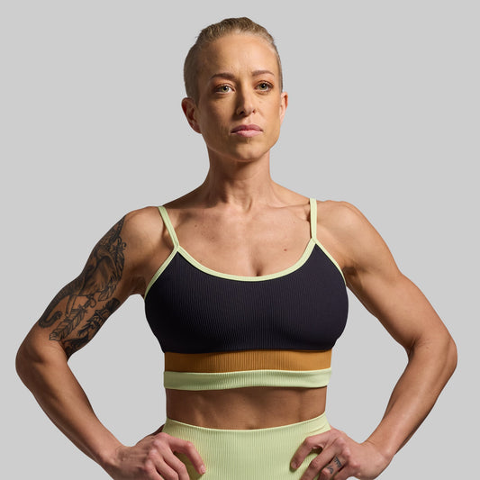 Woman wearing a sports bra and leggings against a gray background