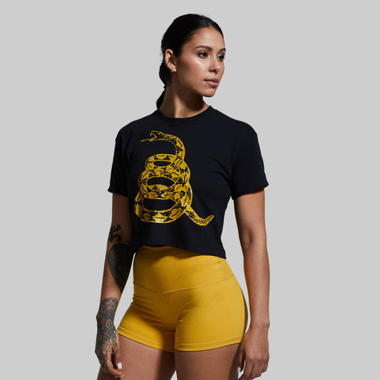 Woman wearing a black t-shirt with a yellow snake design and yellow shorts on a gray background