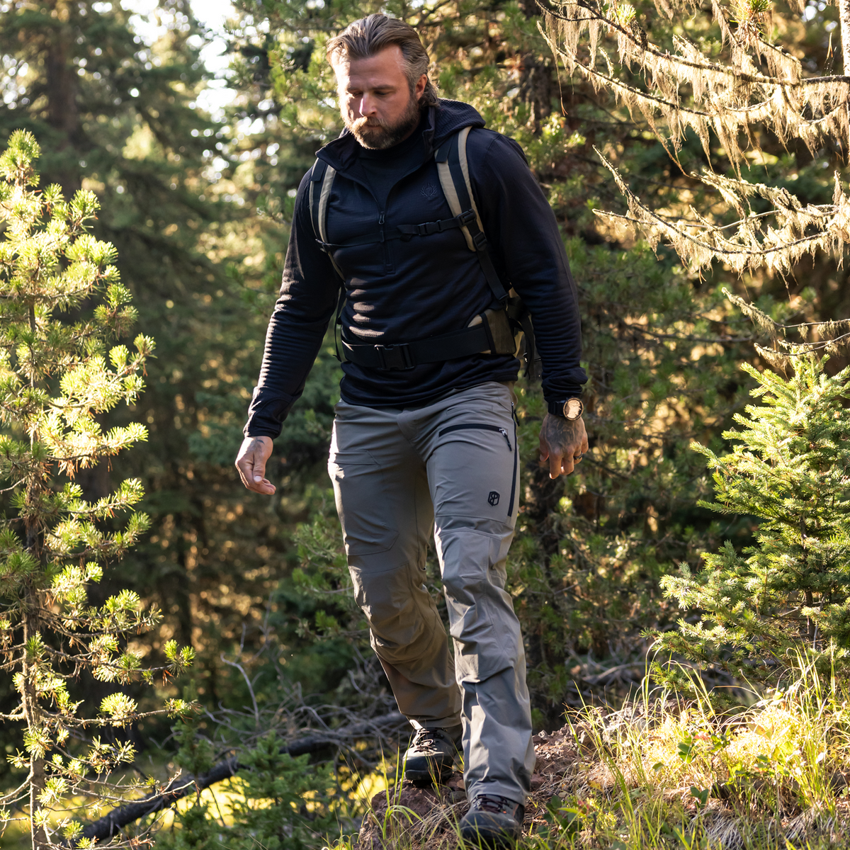 Man hiking through a forest wearing outdoor gear