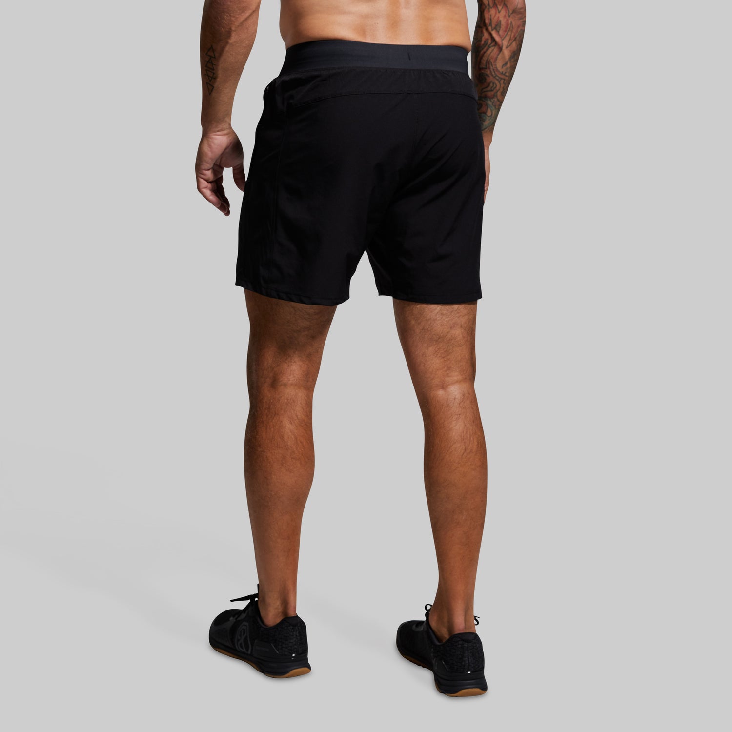 Person wearing black athletic shorts on a gray background
