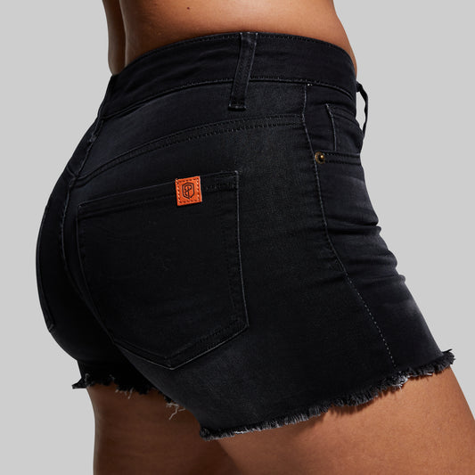 Black denim shorts with a brand logo on the back pocket against a gray background