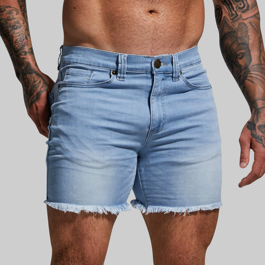 Light blue denim shorts worn by a person with tattoos on a gray background