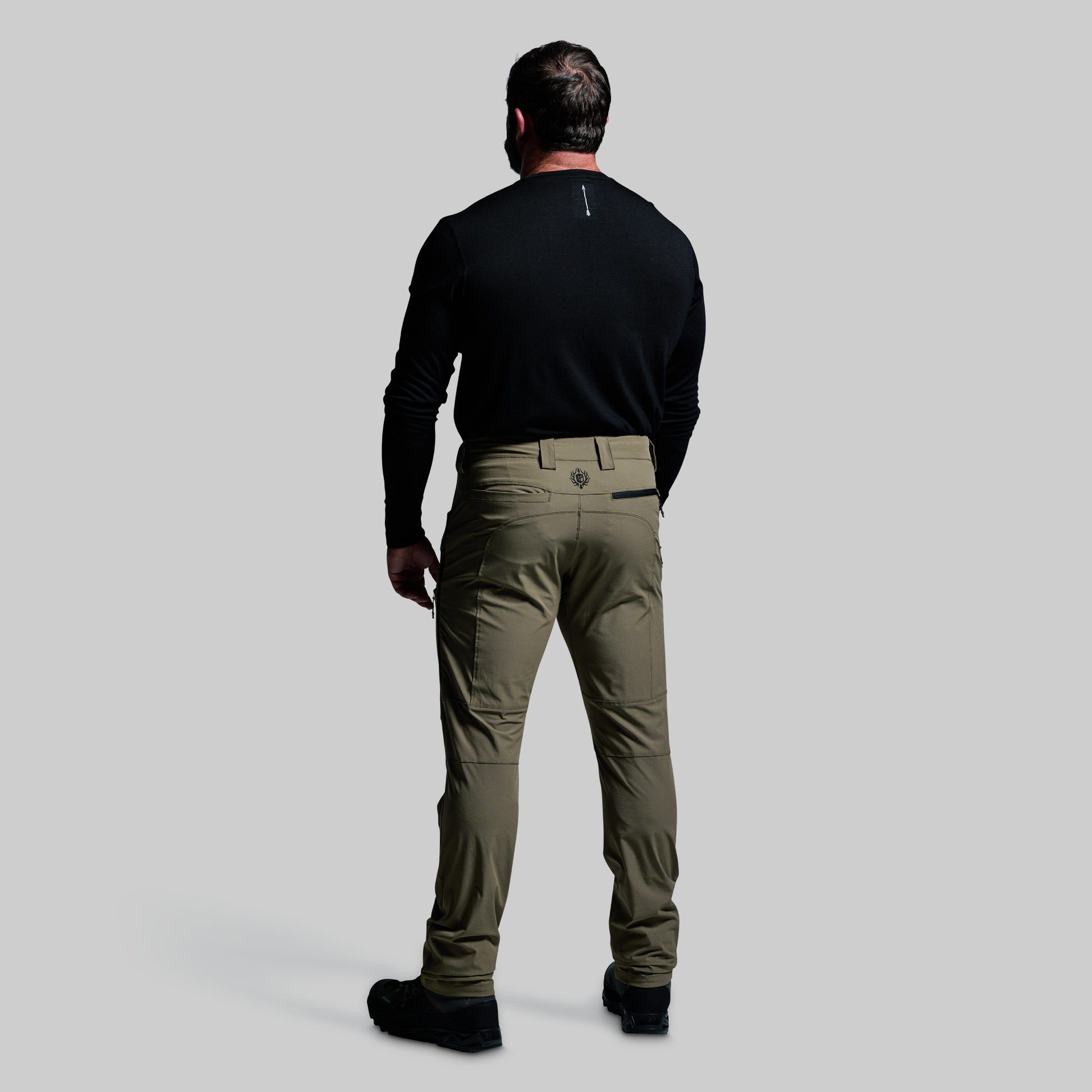 Man wearing a black shirt and green pants on a gray background