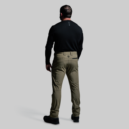 Man wearing a black shirt and green pants on a gray background