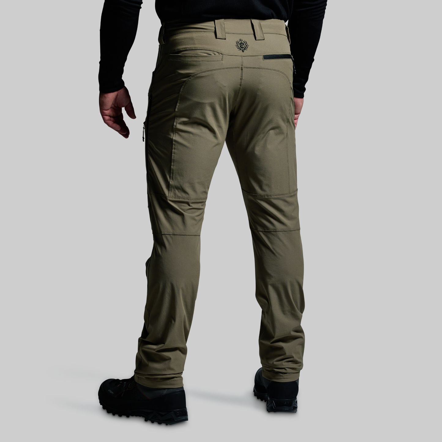 Person wearing olive green outdoor pants on a gray background