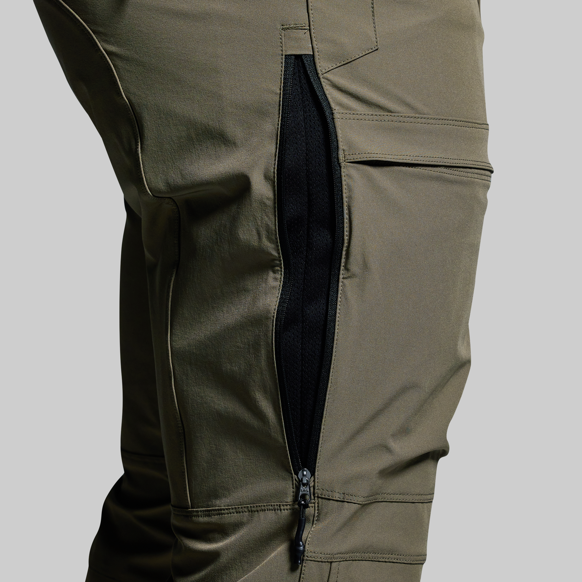 Close-up of olive green pants with a zipper on a gray background