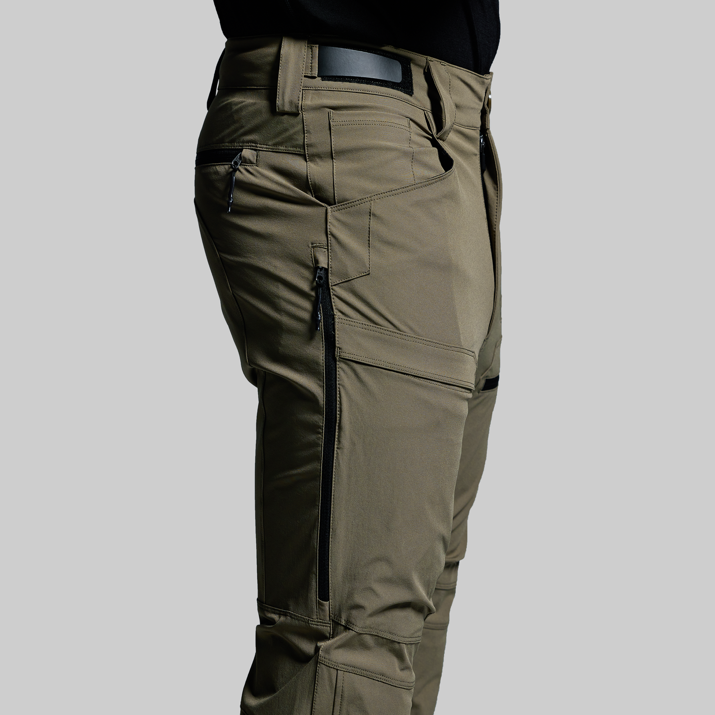 Green outdoor pants with zippers and pockets on a gray background