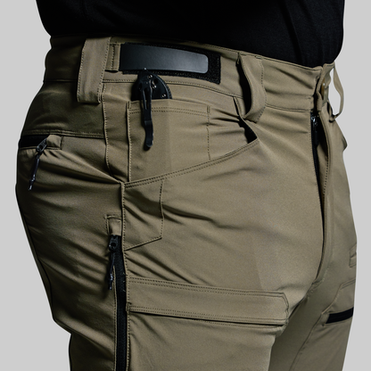 Green outdoor pants with multiple pockets and zippers on a gray background