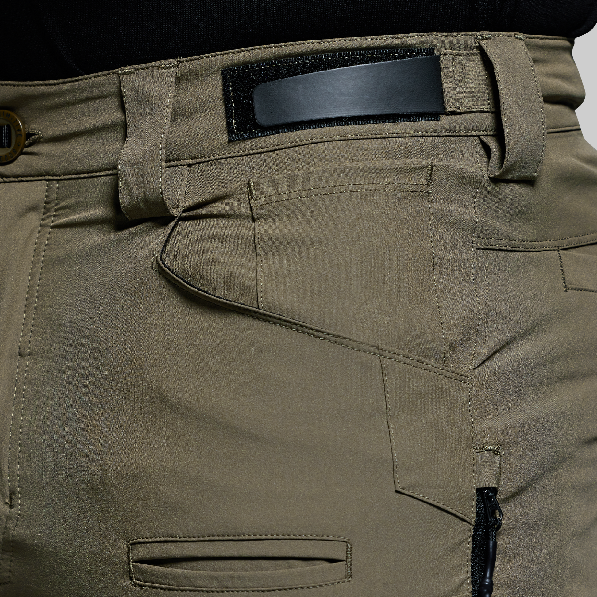 Close-up of olive green outdoor pants with a black adjustable waistband on a white background