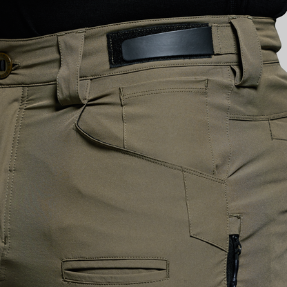 Close-up of olive green outdoor pants with a black adjustable waistband on a white background