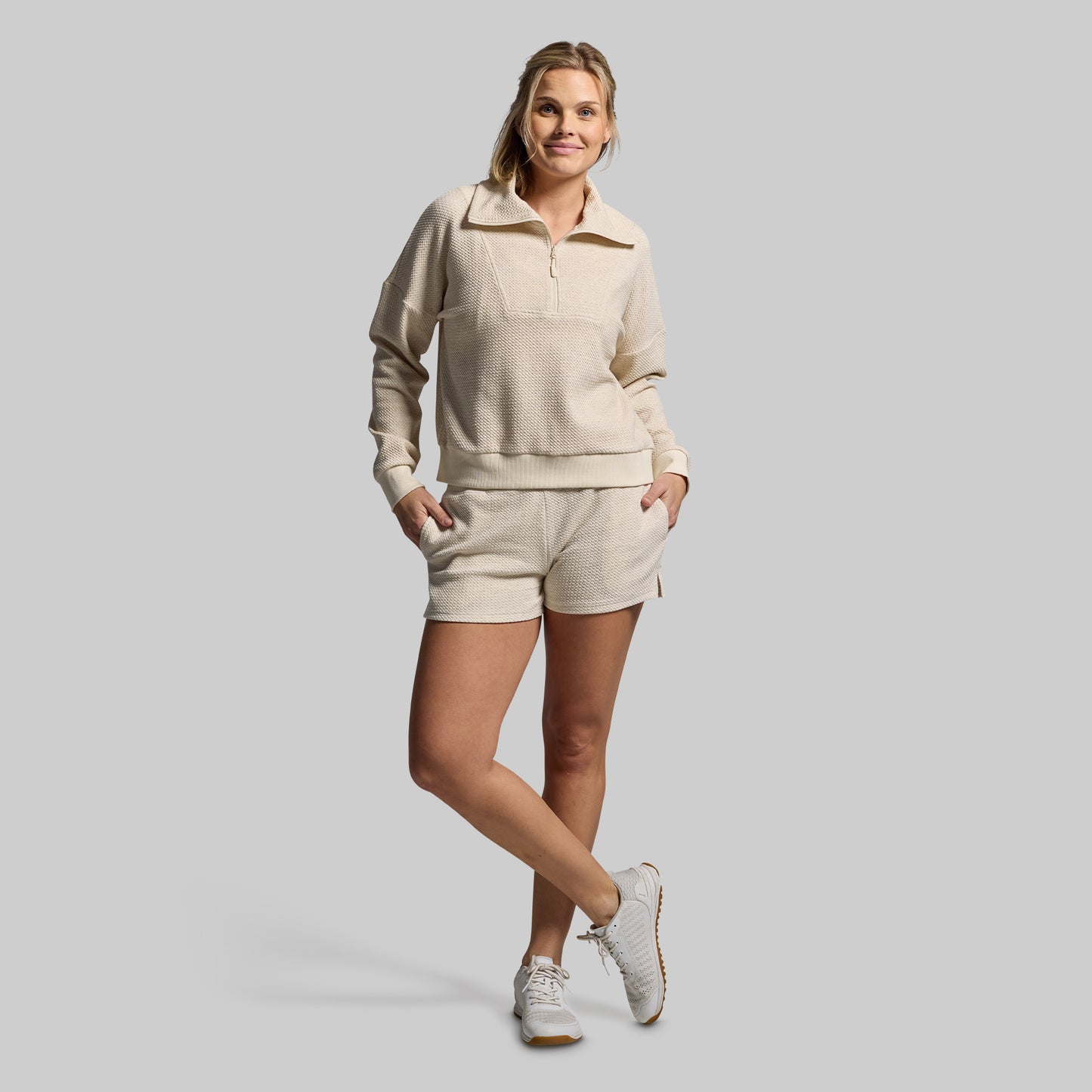 Woman wearing a beige tracksuit on a gray background