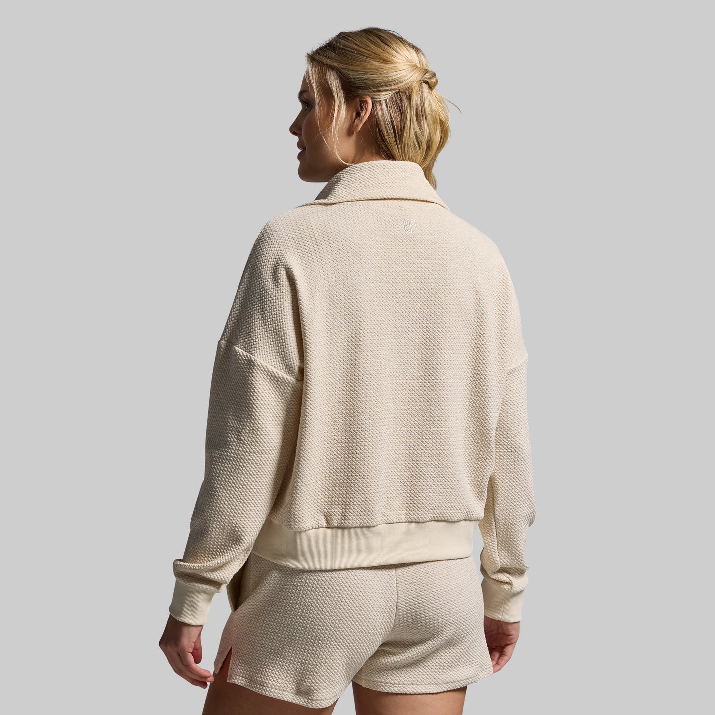Woman wearing a beige tracksuit against a plain background