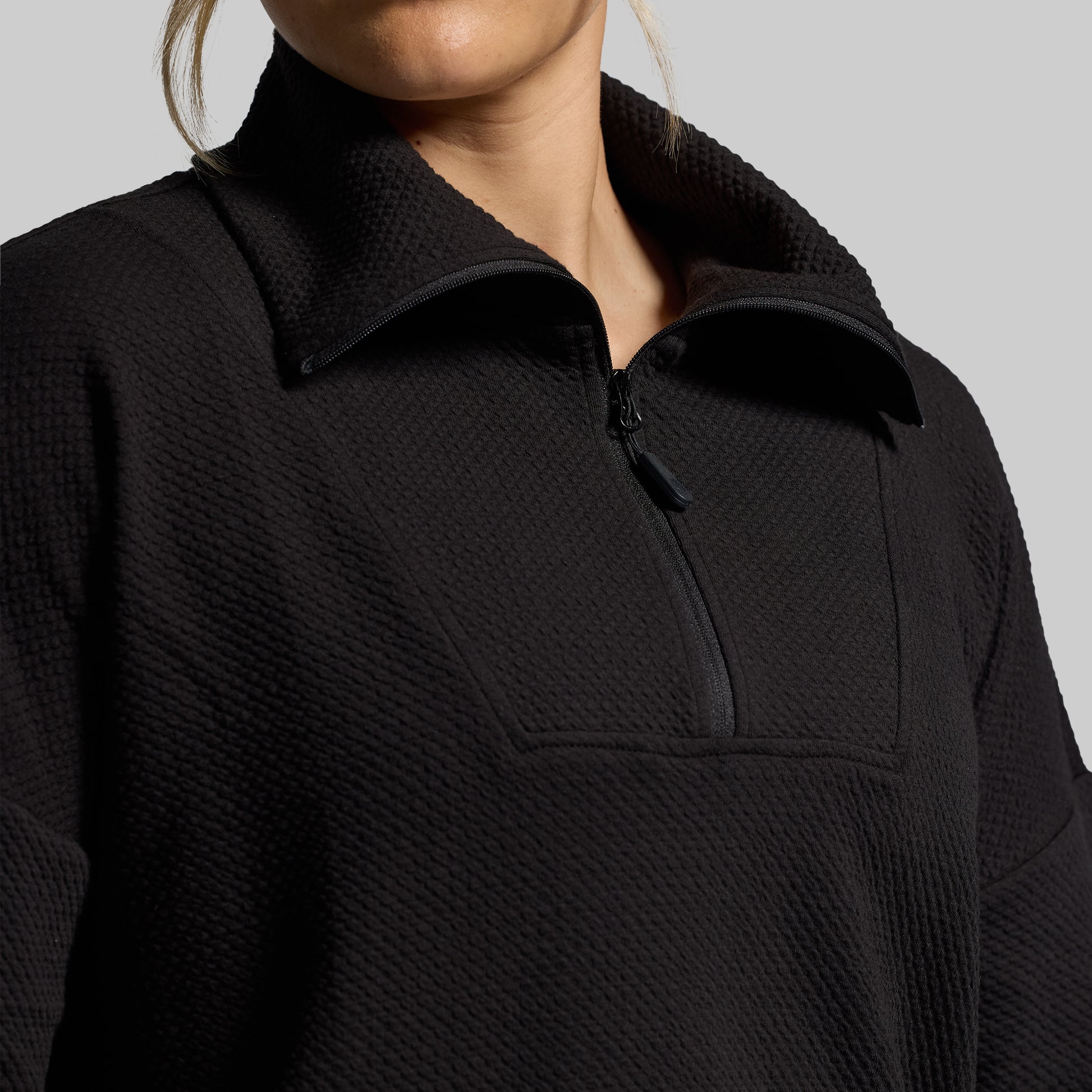 Close-up of black, textured quarter-zip sweatshirt.