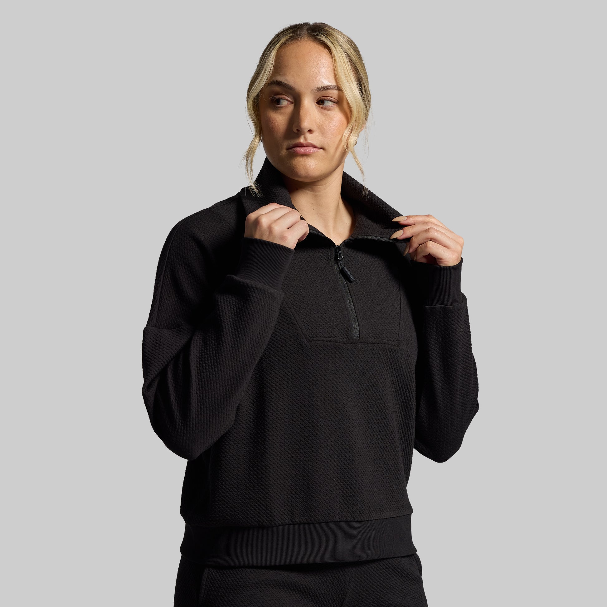 Person wearing a black pullover with a gray background