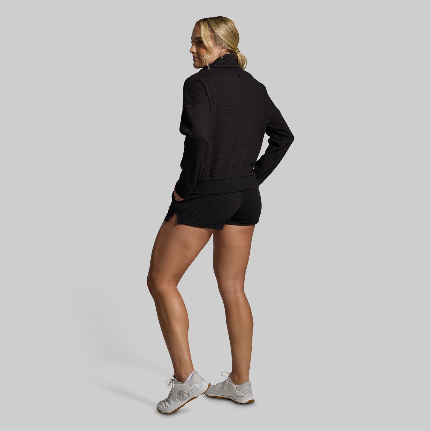 Woman wearing a black tracksuit on a gray background