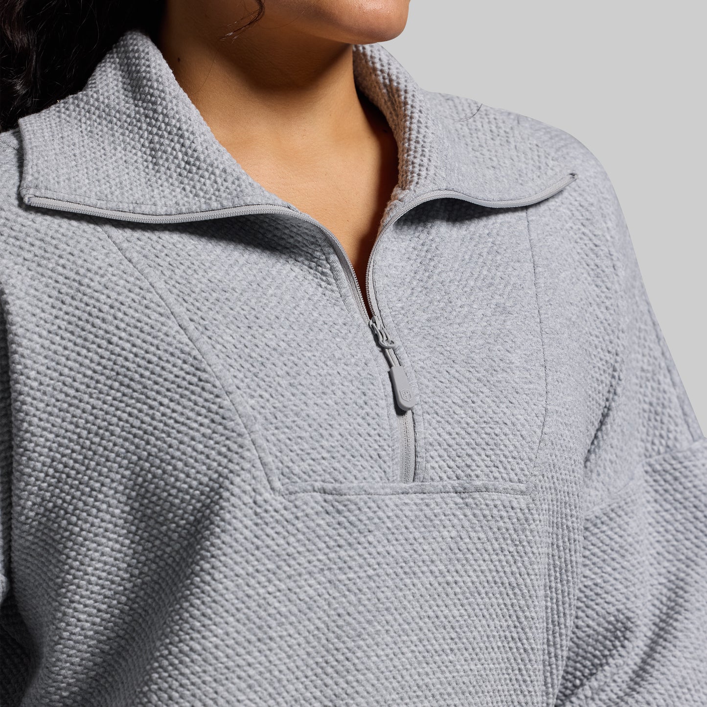 Close-up of a textured gray pullover with a zipper on a neutral background