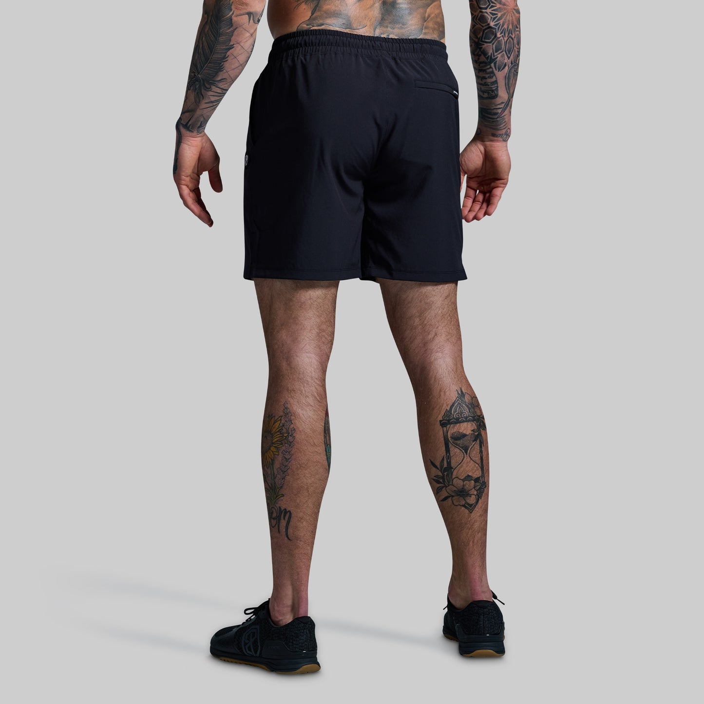 Person wearing black shorts on a plain background