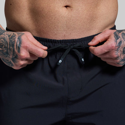 Person wearing black shorts with a focus on the waistband.