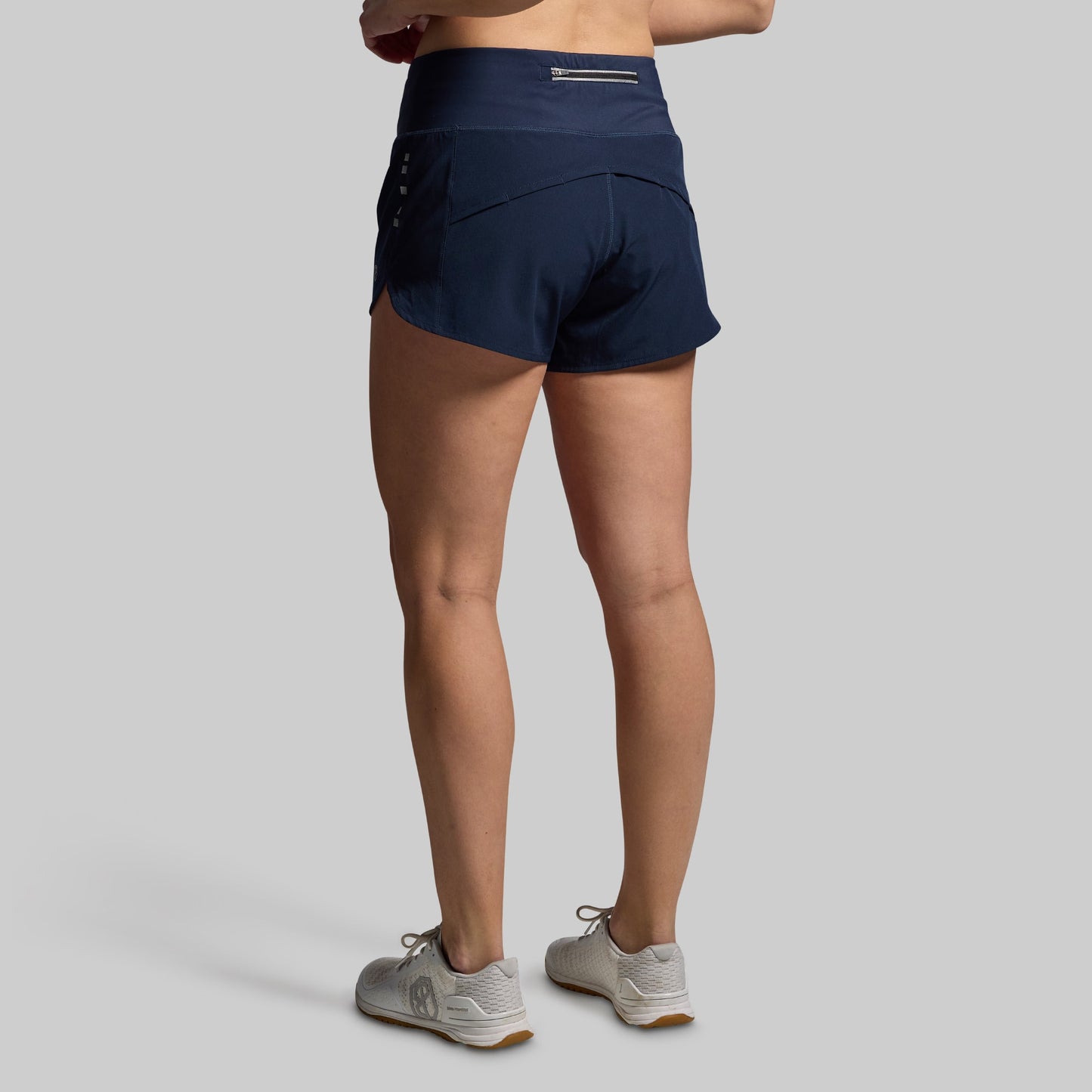 Navy athletic shorts worn by a person on a gray background