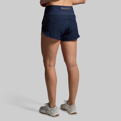 Navy athletic shorts worn by a person on a gray background