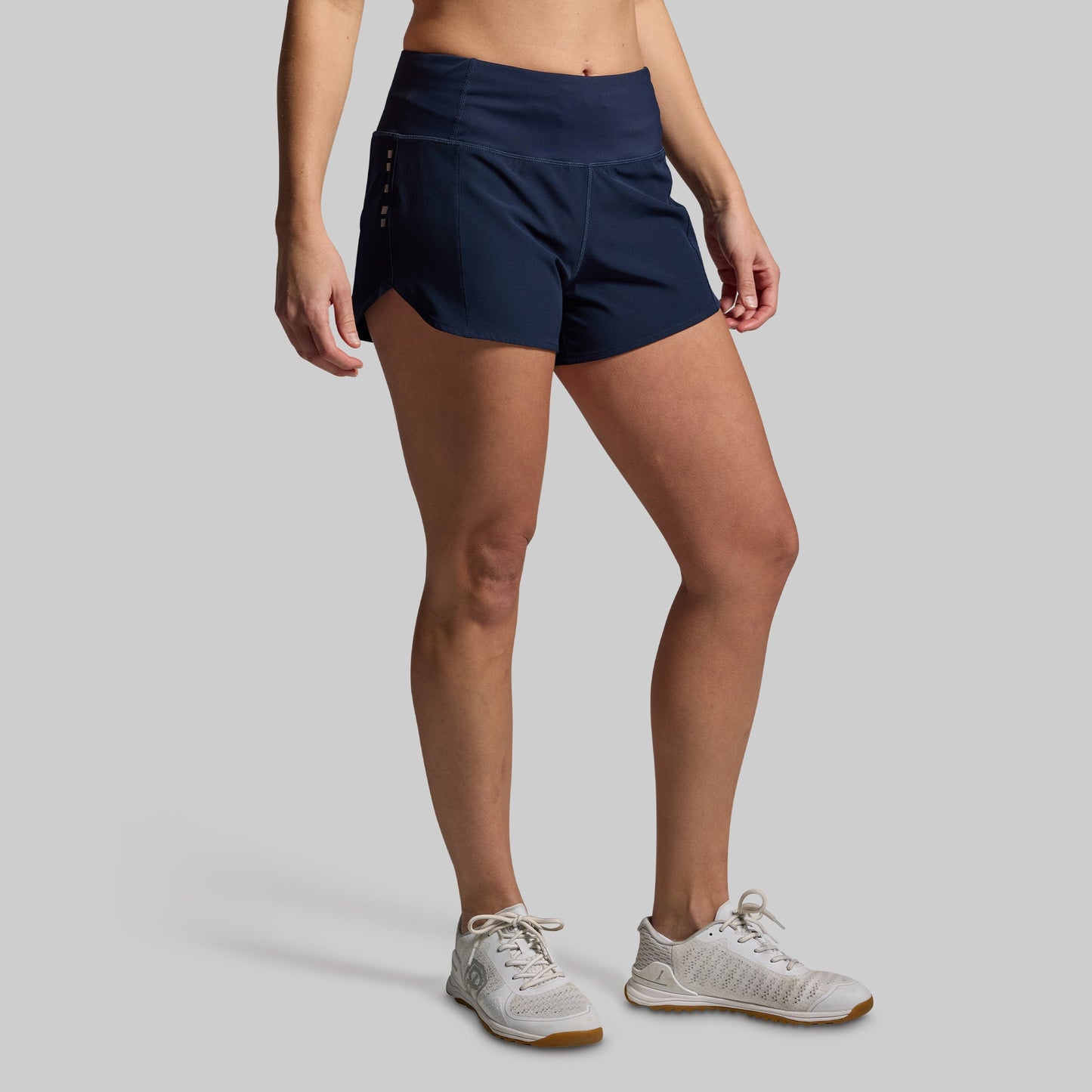 Person wearing navy athletic shorts on a gray background