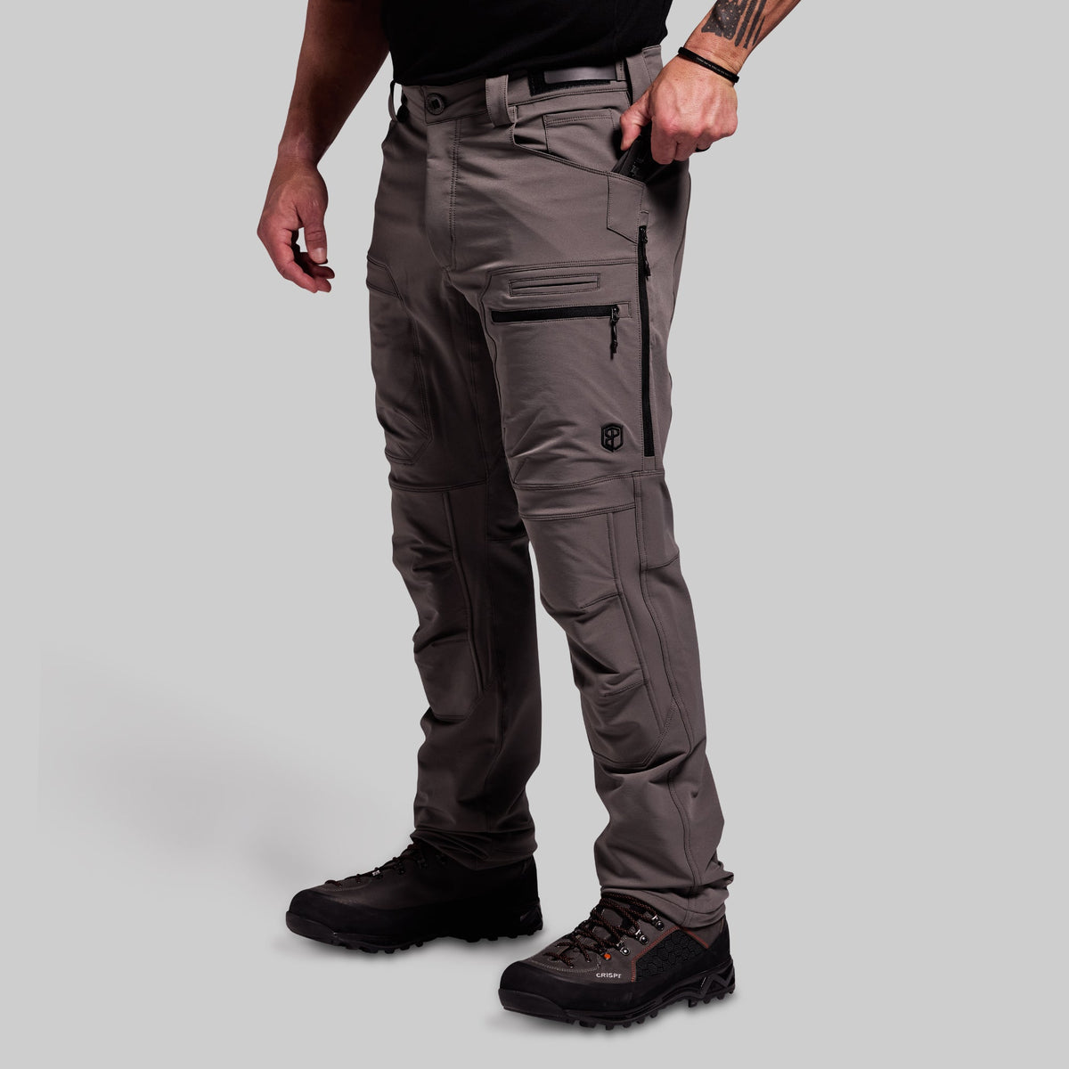Person wearing gray outdoor pants with multiple pockets on a light gray background